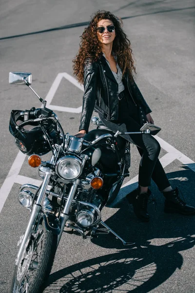 Heureux motard femme assis sur la moto classique sur le parking urbain — Photo de stock
