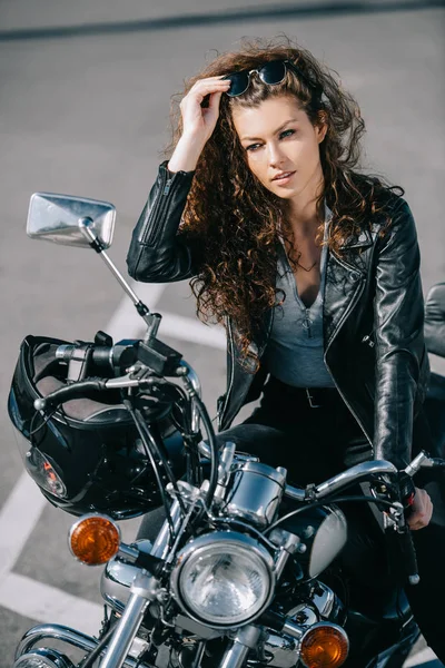 Belle femme assise sur une moto avec casque — Photo de stock