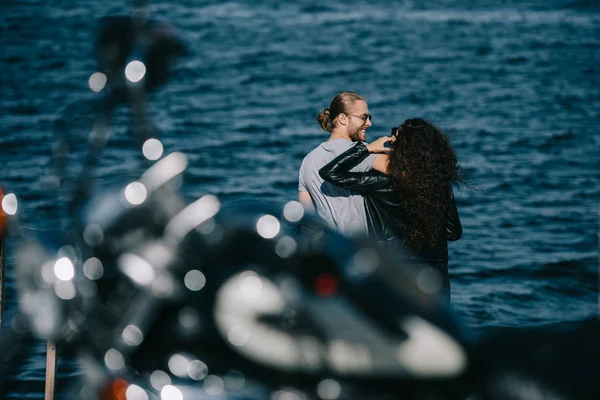 Байкеры обнимаются у моря с мотоциклом на переднем плане — стоковое фото