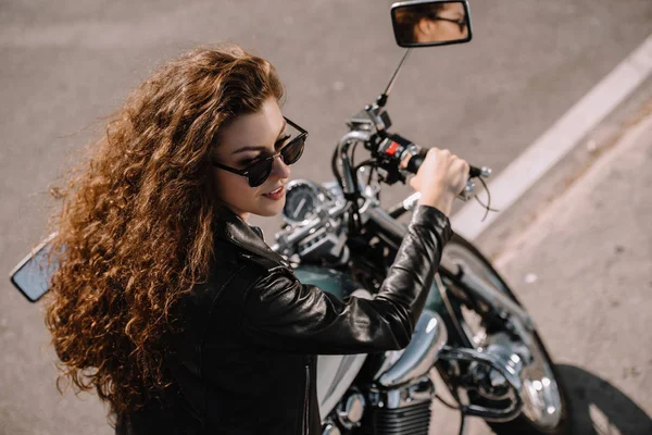 Belle fille assise sur la moto classique sur le parking — Photo de stock