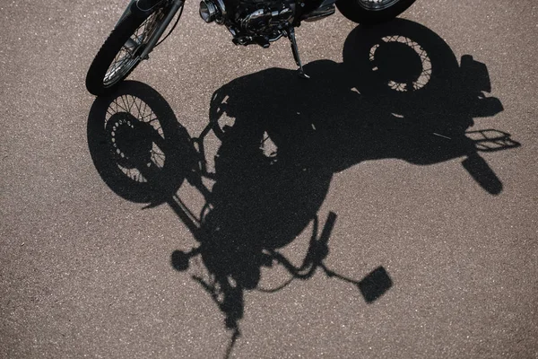 Cropped view of motorbike with shadow on asphalt road — Stock Photo
