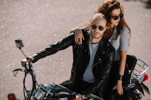 Молодая пара, сидящая на классическом мотоцикле на асфальтовой дороге — стоковое фото