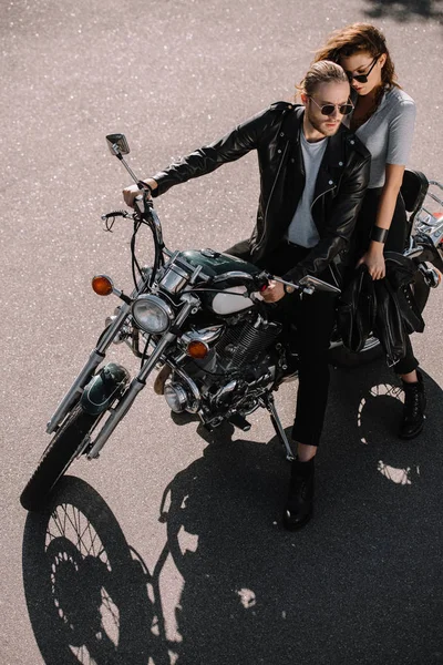 Пара байкеров, сидящих на классическом мотоцикле на асфальтированной дороге — стоковое фото
