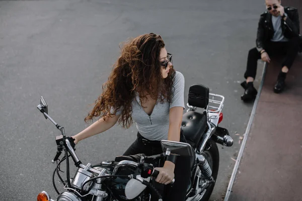 Girl sitting on classical motorbike while her boyfriend sitting on asphalt road — Stock Photo