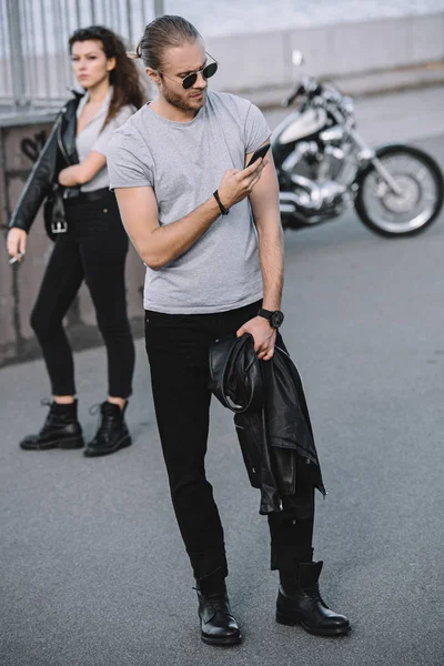 Man using smartphone while woman standing with classical motorbike — Stock Photo