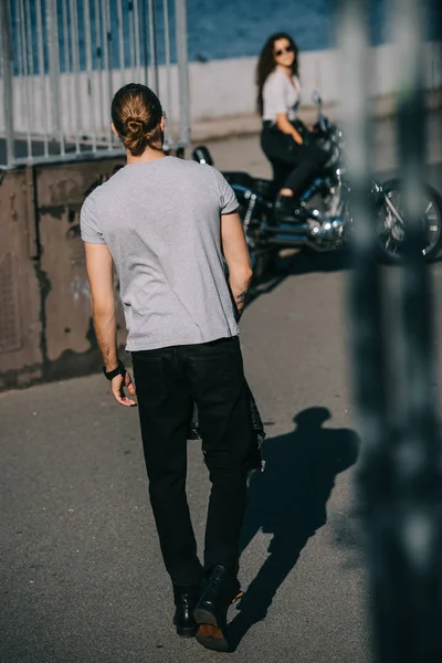 Selective focus of man going to girlfriend with cruiser motorbike — Stock Photo
