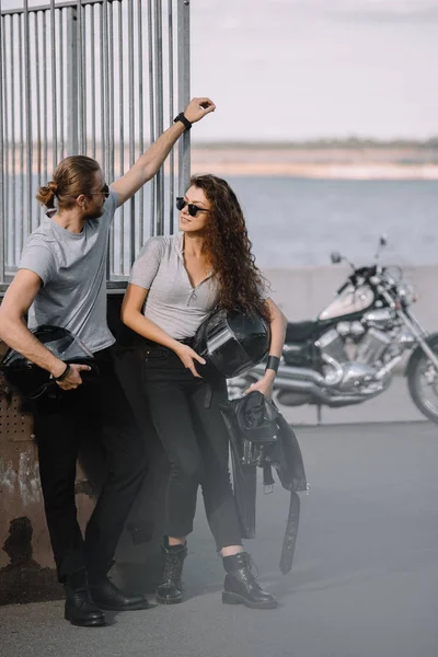 Couple of bikers holding helmets, classical chopper motorcycle on background — Stock Photo