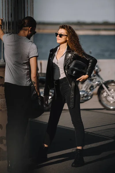 Young couple with helmets standing near classical motorbike — Stock Photo