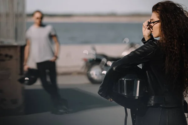 Girl holding helmet and going to boyfriend with motorbike — Stock Photo