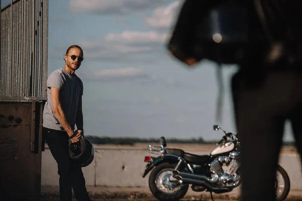 Hombre sosteniendo el casco y mirando a la novia, moto clásica cerca - foto de stock