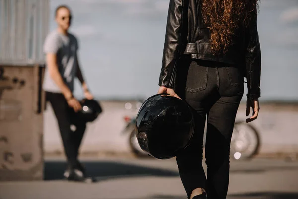 Jovem casal de motoqueiros com capacetes e motocicleta — Fotografia de Stock