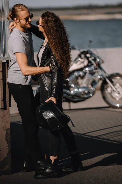 Femme et homme embrassant en ville avec moto sur fond — Photo de stock