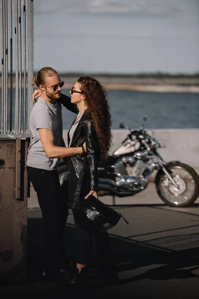Young bikers hugging in city with vintage motorbike on background — Stock Photo