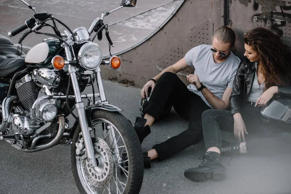 Petite amie et petit ami assis sur asphalte avec moto hachoir classique — Photo de stock