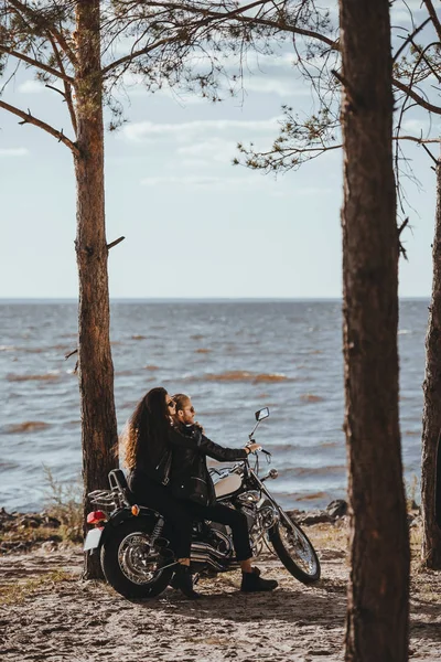 Bikers in black leather jackets sitting on cruiser motorcycle on seashore — Stock Photo