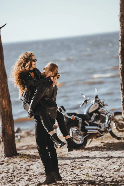 Couple having fun on seashore with chopper motorcycle near — Stock Photo