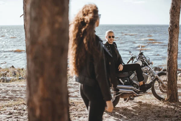 Foco seletivo da mulher olhando para motociclista sentado na motocicleta clássica na costa — Fotografia de Stock