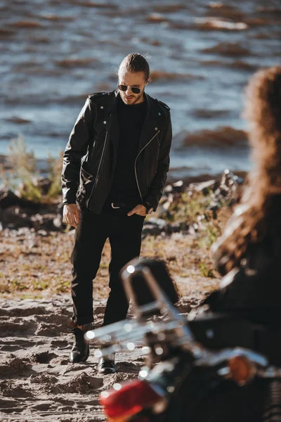 Selective focus of girl sitting on motorbike and looking at boyfriend in black leather jacket — Stock Photo