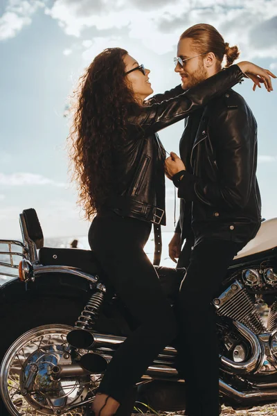 Couple in black leather jackets hugging on vintage motorbike — Stock Photo