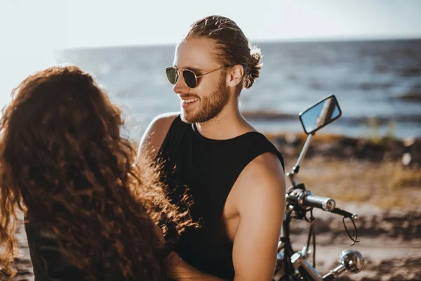 Couple souriant passer du temps ensemble près de la mer avec moto — Photo de stock