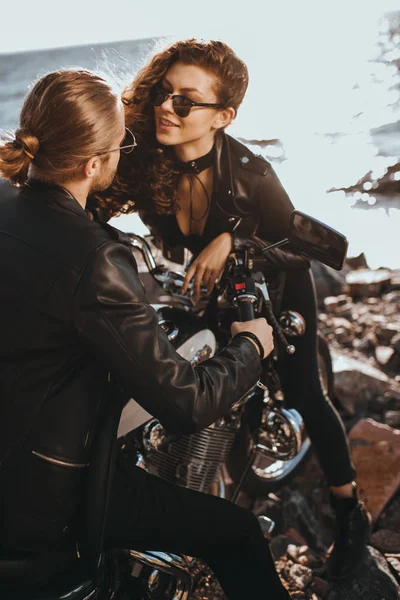 Feliz chica coqueteando con su novio mientras él sentado en moto clásica - foto de stock