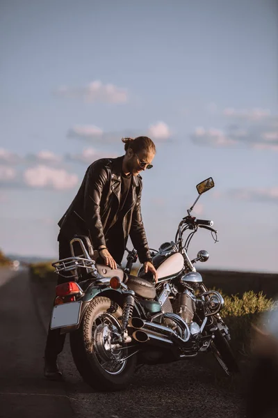 Handsome male biker with classical motorcycle on road — Stock Photo