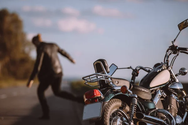 Motocicleta clásica rota en la carretera con motociclista enojado en el fondo, enfoque selectivo - foto de stock