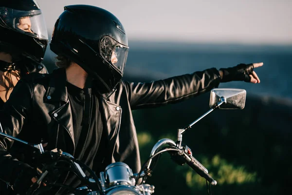 Couple de motards dans les casques sur la moto, homme pointant quelque chose — Photo de stock
