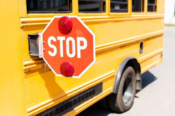 Cropped shot of traditional school bus with stop road sign — Stock Photo