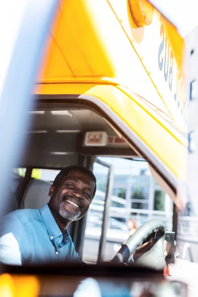 Щасливий зрілий афроамериканський водій автобуса дивиться на камеру — стокове фото