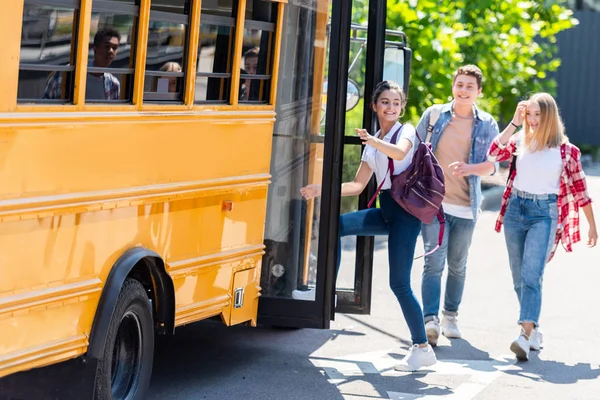 Felici studenti adolescenti che camminano in scuolabus — Foto stock