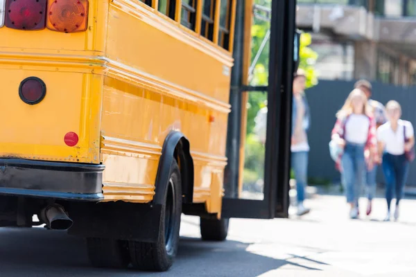 Traditioneller amerikanischer Schulbus mit einer Gruppe von Schülern, die unscharf auf dem Hintergrund läuft — Stockfoto