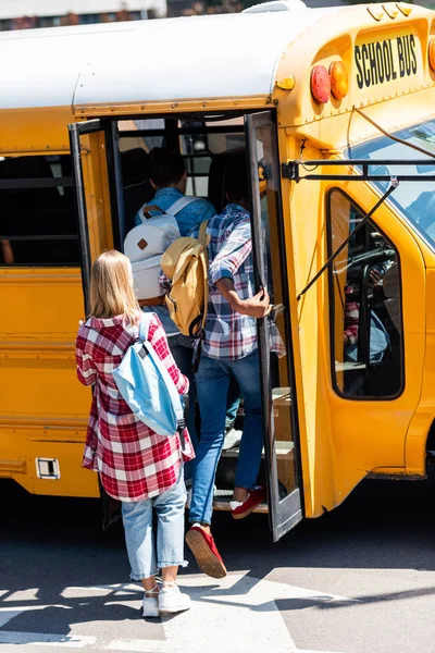 Rückansicht von Teenagern, die in Schulbus einsteigen — Stockfoto