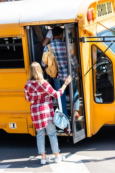 Rear view of teen students walking into school bus — Stock Photo