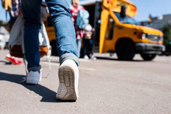 Recortado tiro de estudiante caminando en el autobús escolar con compañeros de clase - foto de stock