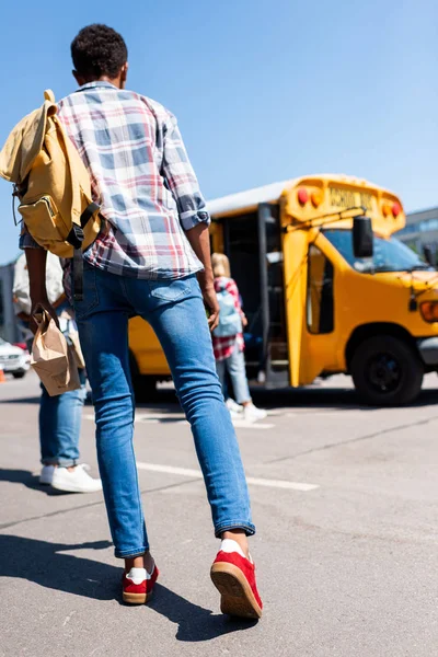 Rear view of teen schoolboy walking at school bus — Stock Photo