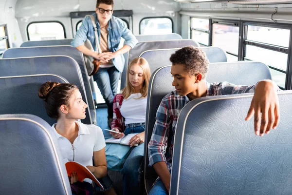 Grupo de adolescentes eruditos montando autobús escolar y pasar tiempo juntos - foto de stock