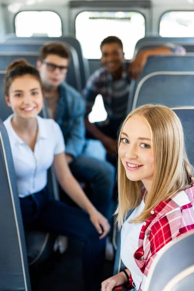 Group of teen scholars riding school bus and looking at camera — Stock Photo