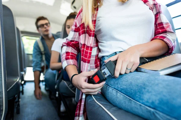 Cropped shot of schoolgirl fastening seat belt at school bus — Stock Photo