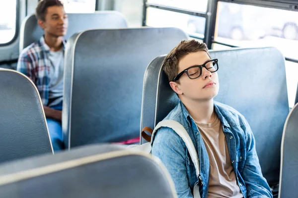 Multiethnic teen schoolboys riding school bus — Stock Photo