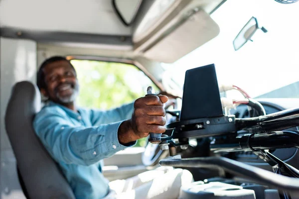 Зрілий афроамериканський водій автобуса тягне важіль в автобусі — стокове фото