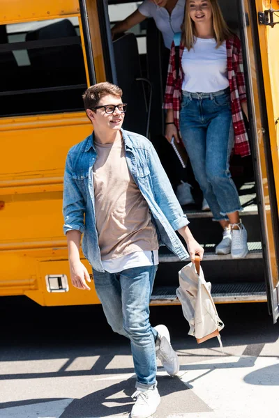 Grupo de estudiantes adolescentes caminando fuera del autobús escolar - foto de stock