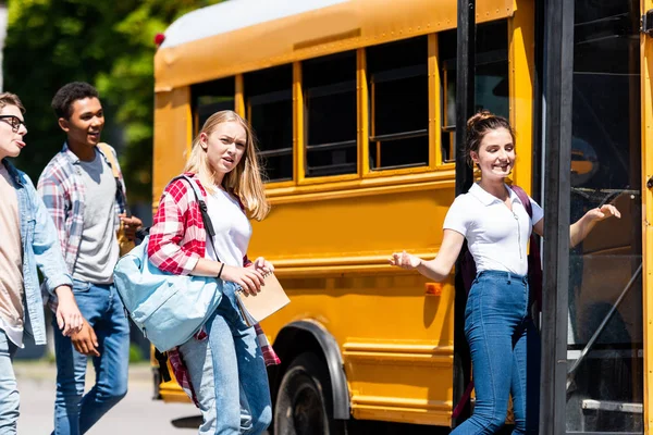 Groupe d'élèves adolescents entrant dans le bus scolaire après les cours — Photo de stock