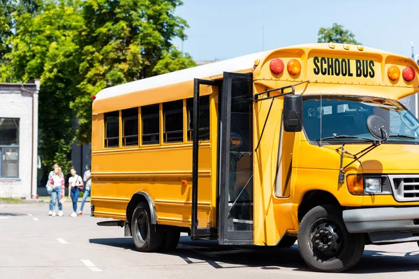 Шкільний автобус стоїть на парковці з розмитими студентами, що ходять на фоні — стокове фото