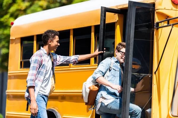 Fröhliche multiethnische Teenager-Schüler, die am Schulbus laufen — Stockfoto