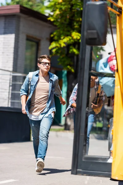 Multiethnic teen schoolboys running at school bus — Stock Photo