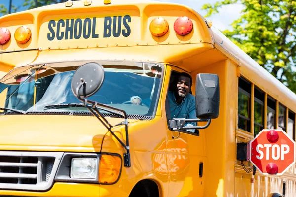 Beau chauffeur de bus scolaire senior regardant la caméra par la fenêtre — Photo de stock