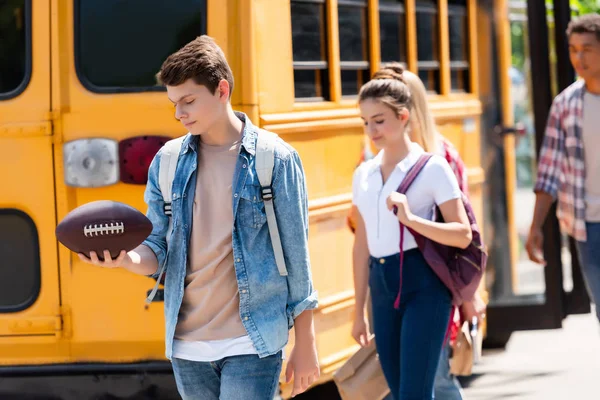 Grupo de estudiantes adolescentes felices caminando frente al autobús escolar - foto de stock
