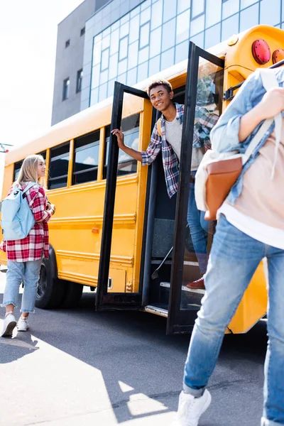 Étudiants adolescents multiethniques sortant de l'autobus scolaire — Photo de stock