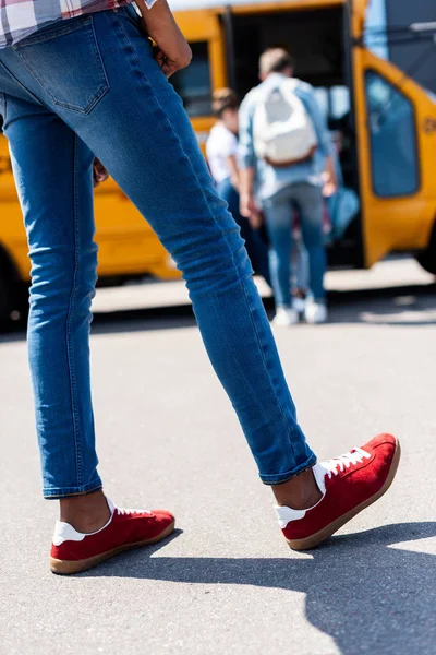 Cropped shot of african american boy standing in front of school bus — Stock Photo